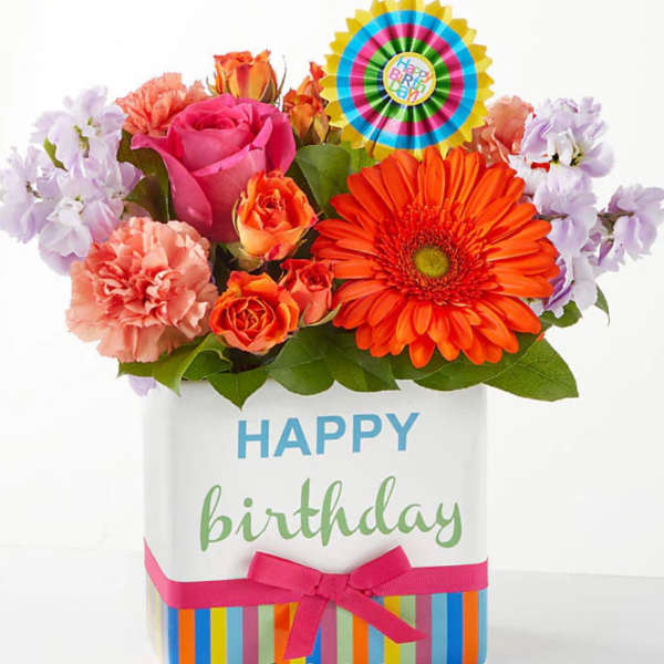 Birthday flower arrangement in a decorated gift box with a colorful topper