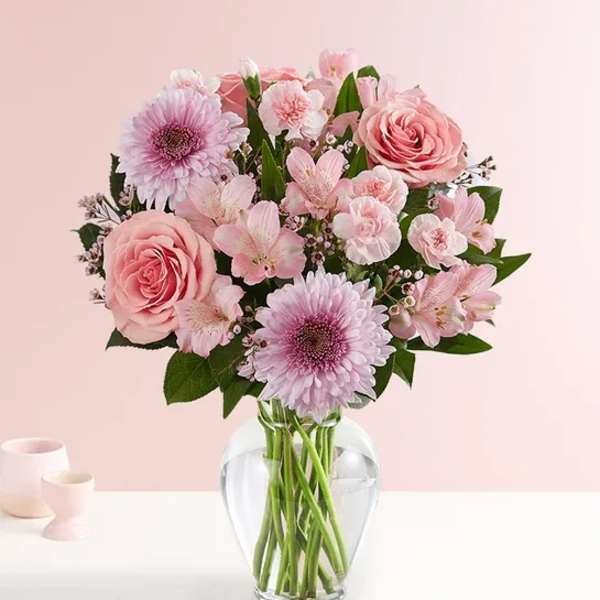 Pink bouquet of roses, daisies, and alstroemeria in a clear vase