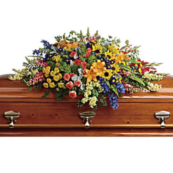 Large colorful floral spray on a wooden casket