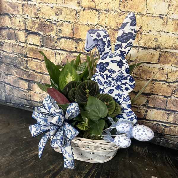 Green houseplants in a white basket with blue patterned bunny and egg decorations