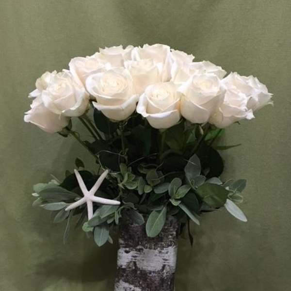 White roses in a birch vase with greenery and a starfish accent