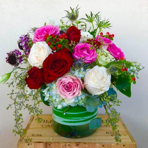 Bouquet of red, pink, and white roses in a green glass vase