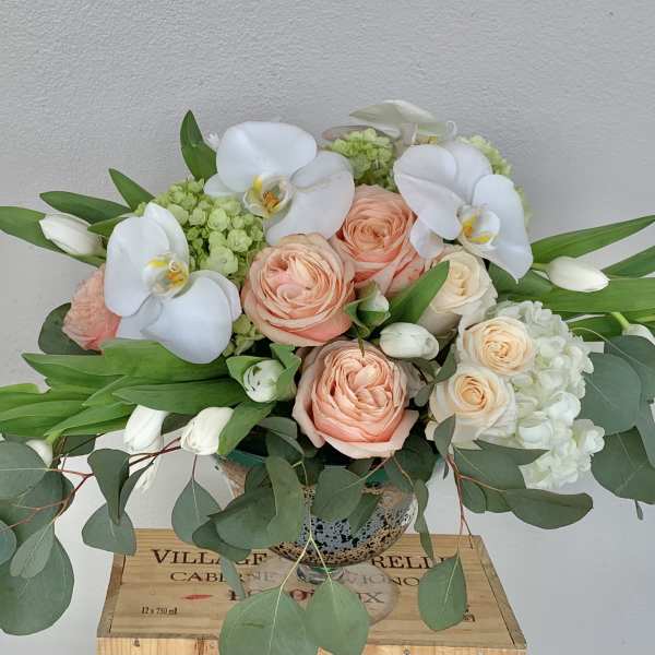 Peach roses and white orchids in a glass vase