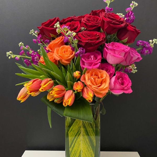 Bouquet of red, pink, and orange roses in a glass vase