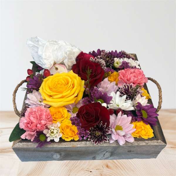 Mixed bouquet of roses and daisies in a wooden tray