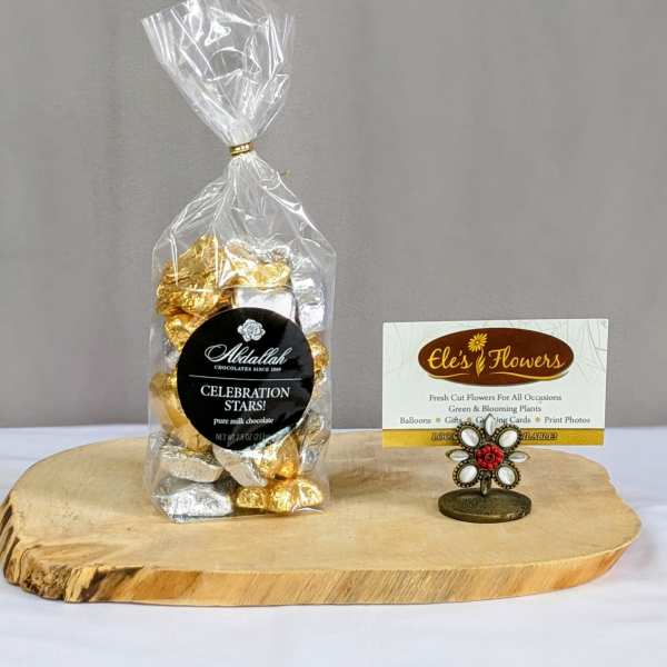 Bag of gold and silver wrapped chocolates with a business card holder on a wooden board