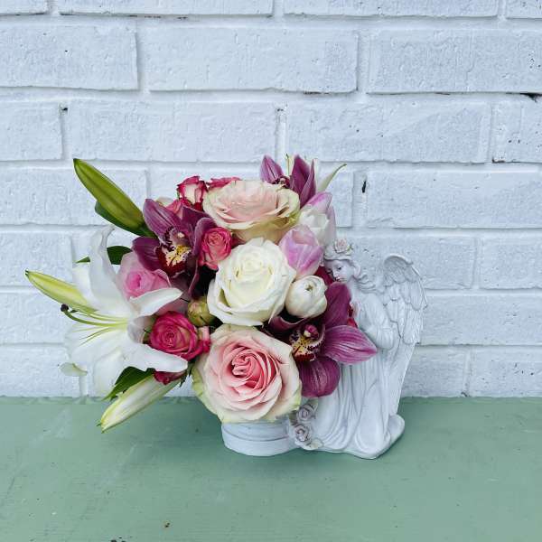 Pink and white rose bouquet with lilies in a white angel vase