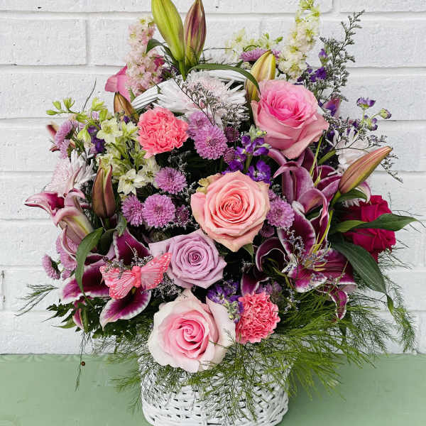Pink and purple mixed flower arrangement in a white basket