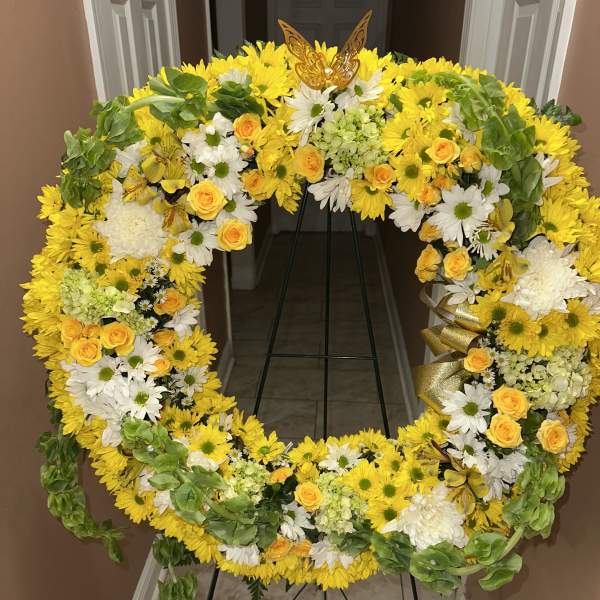 Large yellow and white floral wreath on a stand