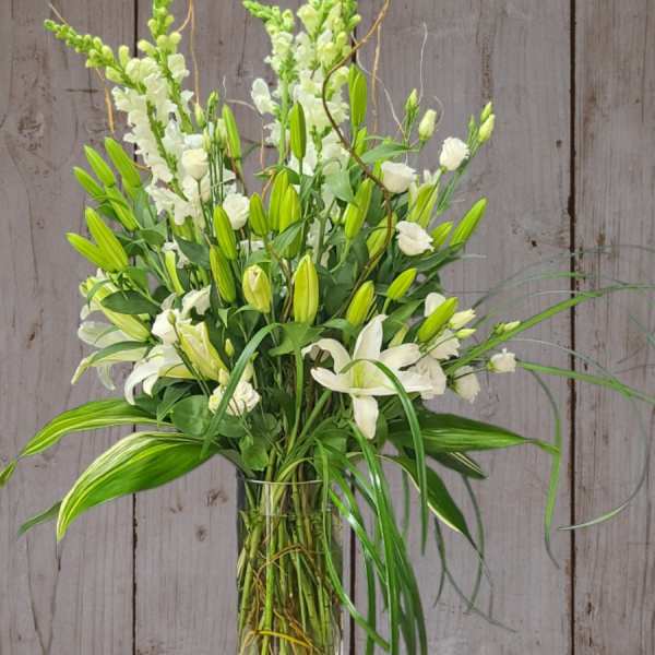 Tall white floral arrangement in a clear glass vase
