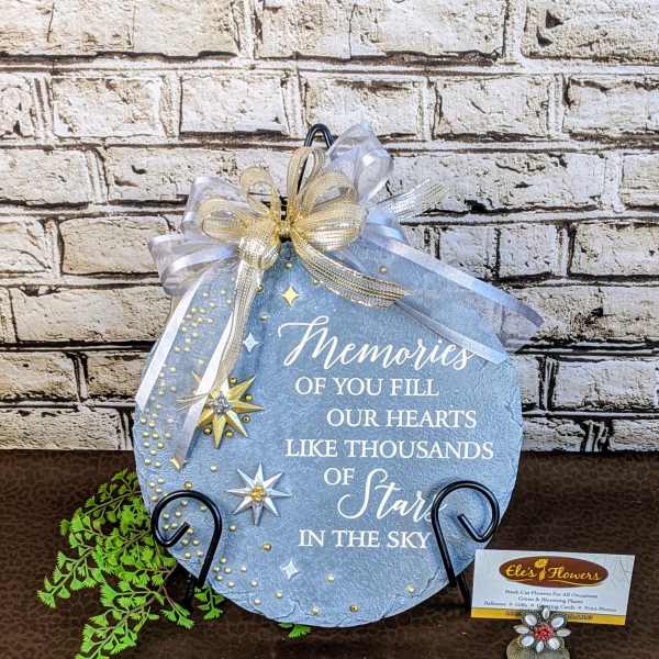 Blue memorial plaque with ribbon and star decorations on a stand