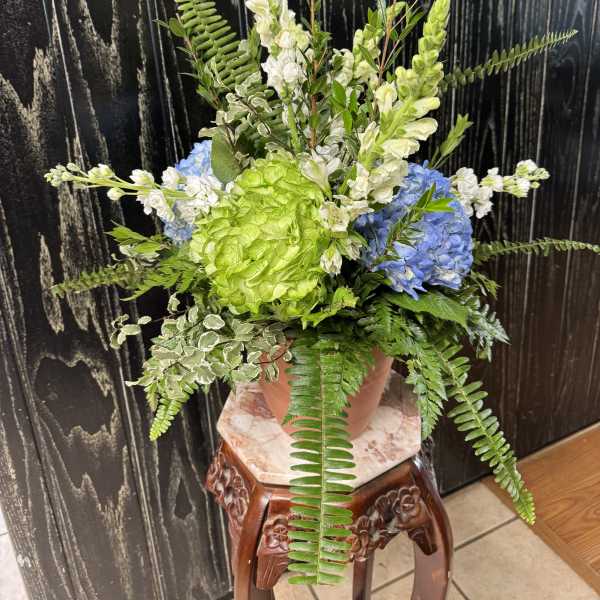Potted floral arrangement with blue hydrangeas, green blooms, and white snapdragons