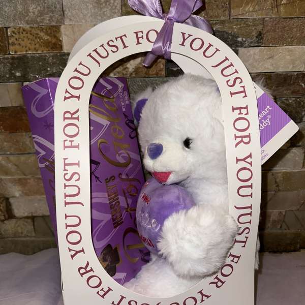 White teddy bear in a purple gift box with a ribbon
