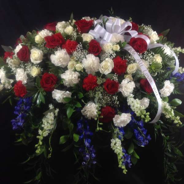 Large red and white floral spray with ribbon on a dark background