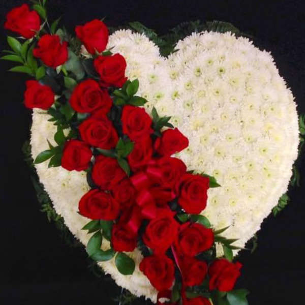 Heart-shaped white floral spray with red roses and ribbon