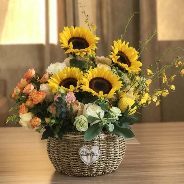 Sunflower and rose arrangement in a woven basket