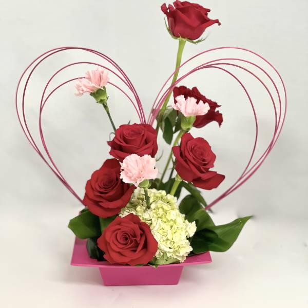 Red roses and pink carnations in a pink heart-shaped container
