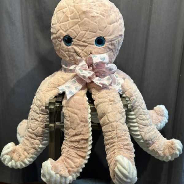 Plush octopus toy with a ribbon bow sitting on a chair