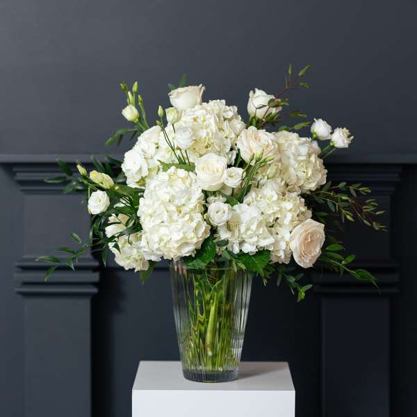 White roses and hydrangeas arranged in a clear glass vase