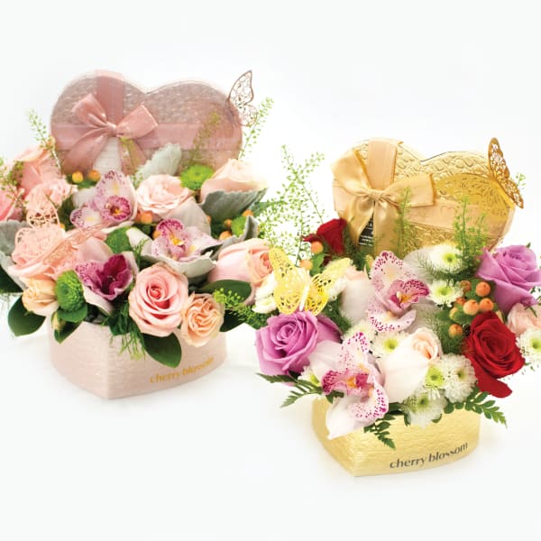 Two heart-shaped floral gift boxes with roses and orchids