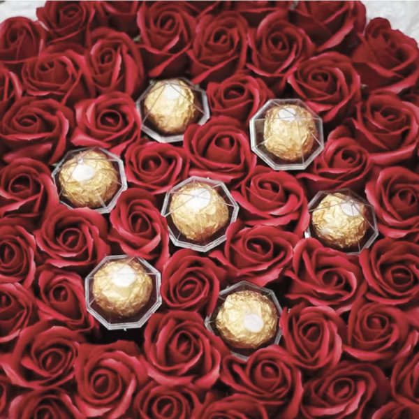 Red roses with gold-wrapped chocolates arranged together