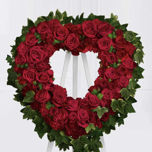 Heart-shaped wreath of red roses on a white stand