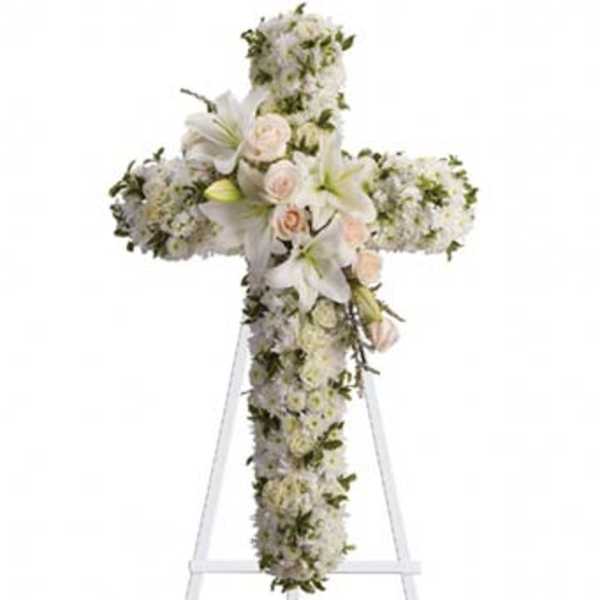 White floral cross arrangement with lilies and roses on a stand