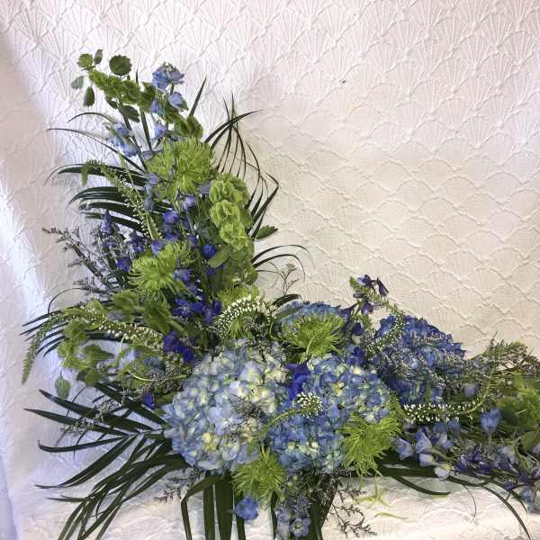 Blue and green floral arrangement with hydrangeas and tall spiky blooms