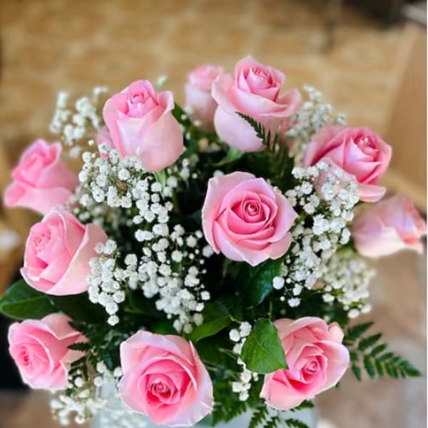 Pink roses arranged with white baby's breath in a vase