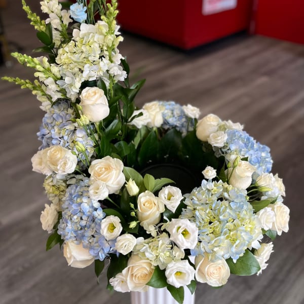 White and blue floral arrangement with roses and hydrangeas in a vase