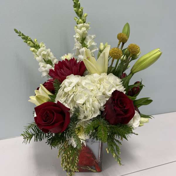 Red roses and white hydrangea in a square vase with lilies and snapdragons