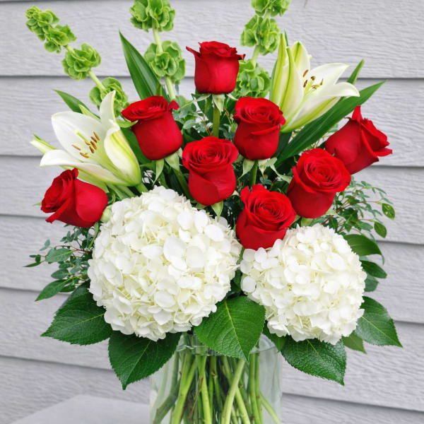 Red roses and white lilies with hydrangeas in a glass vase