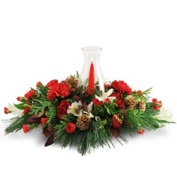 Red carnations and pine arranged around a red taper candle in a glass hurricane