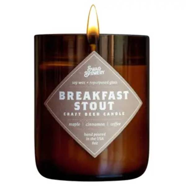 Brown glass jar candle labeled Breakfast Stout with a lit flame