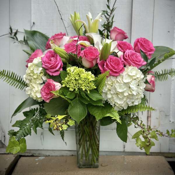 Pink roses and white lilies in a glass vase with white hydrangeas