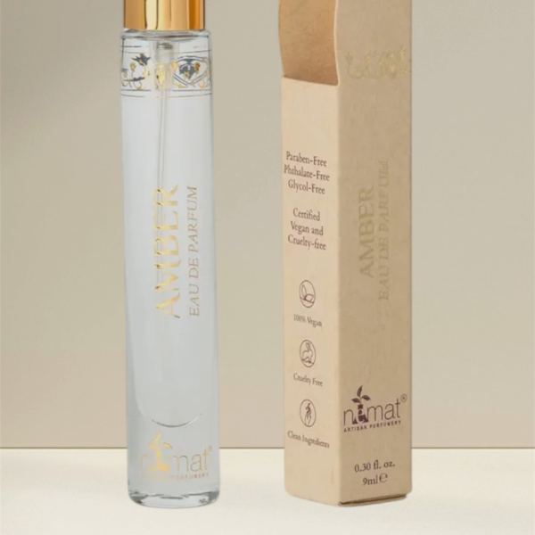 A perfume bottle with a gold cap beside its beige box