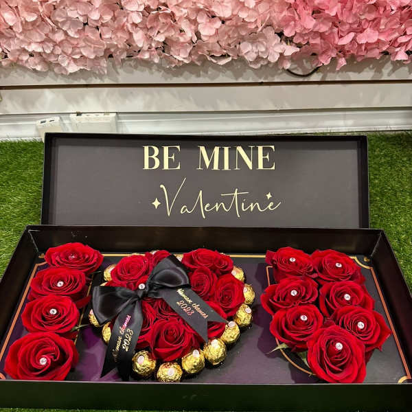 Red roses arranged in a gift box with chocolates and a Valentine sign