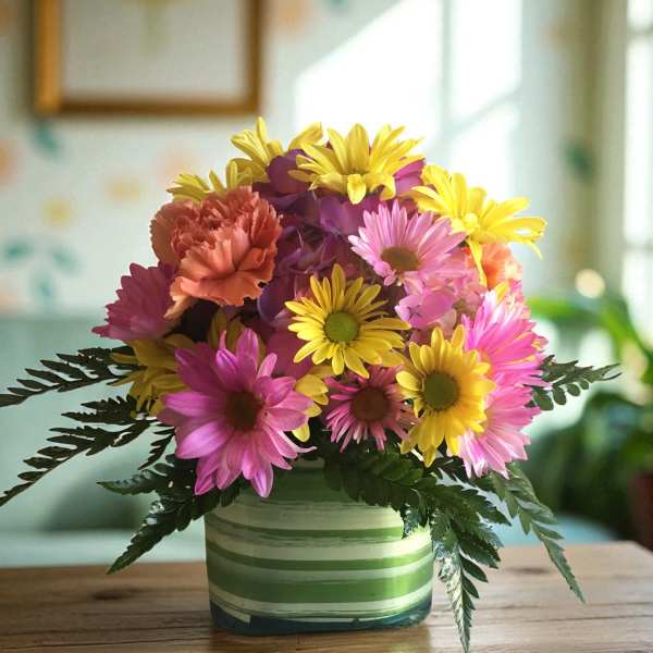 Colorful bouquet of daisies and carnations in a striped ceramic vase