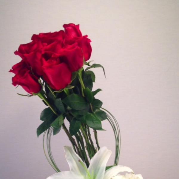 Red roses with a white lily and white hydrangea in a glass vase