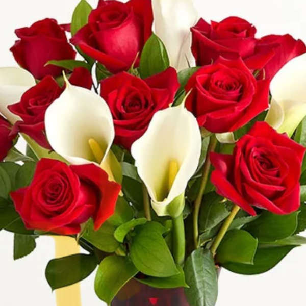 Red roses and white calla lilies in a red glass vase