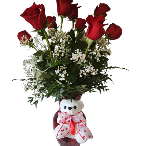Red roses in a vase with a teddy bear bow