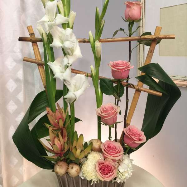 Tall floral arrangement with pink roses and white gladiolus in a rectangular vase