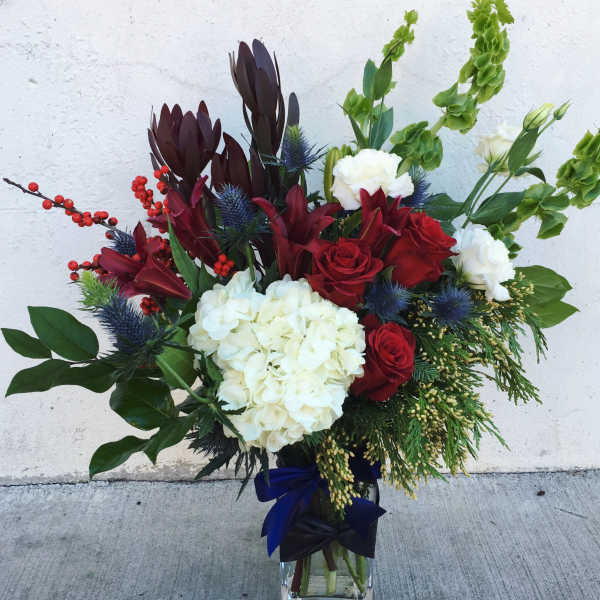 Bouquet of red and white flowers in a glass vase with blue ribbon