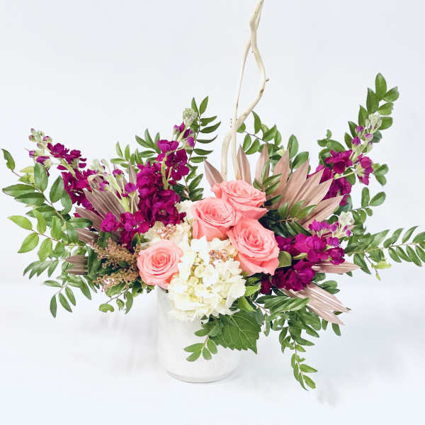 Pink roses and white hydrangea in a white vase with purple flowers