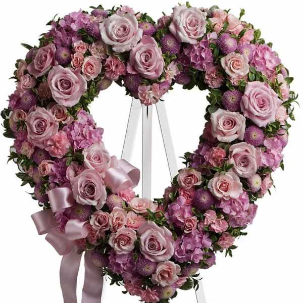 Heart-shaped pink and lavender floral wreath on an easel with ribbon