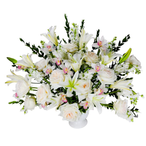 White lilies and roses arranged in a low white vase