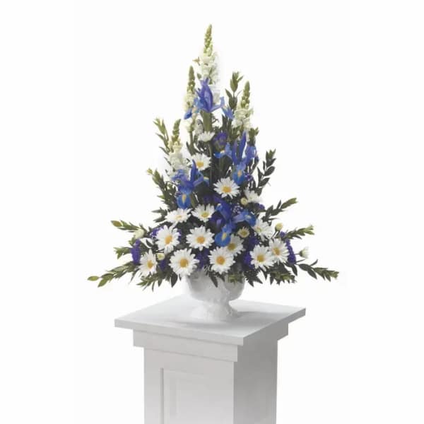 Tall white and blue floral arrangement in a white urn