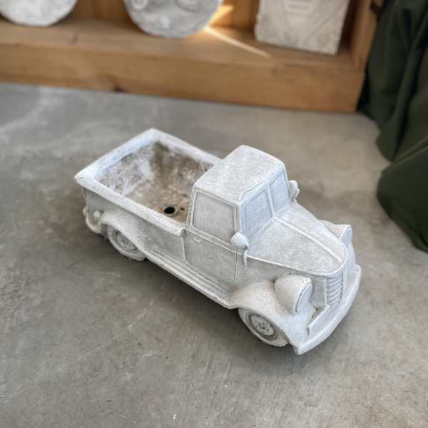 White pickup truck-shaped planter on a concrete floor