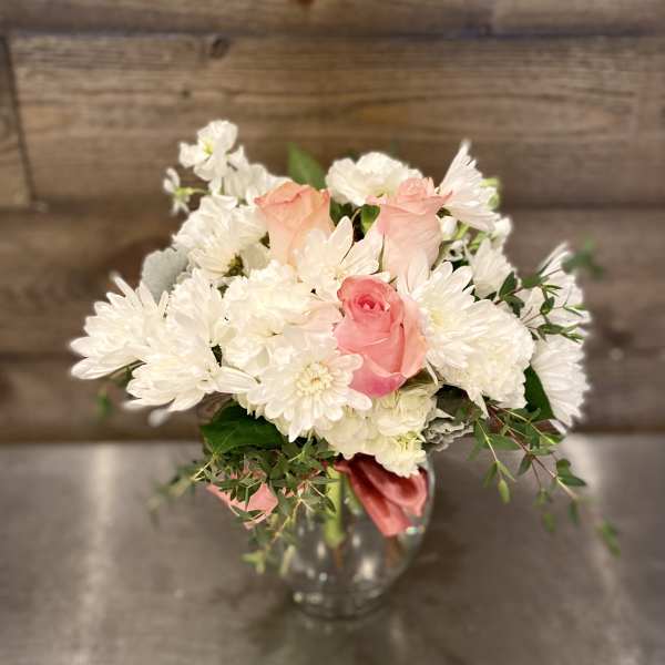 Pink roses and white daisies arranged in a clear glass vase