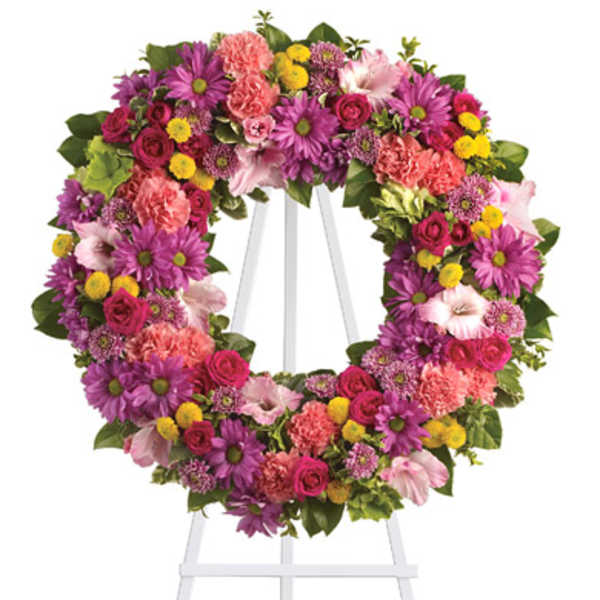 Heart-shaped floral wreath on a white easel with pink, purple, and yellow blooms